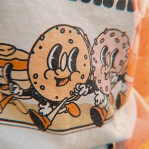 zoomed in detail of a retro graphic of a bagel and donut and pancakes walking