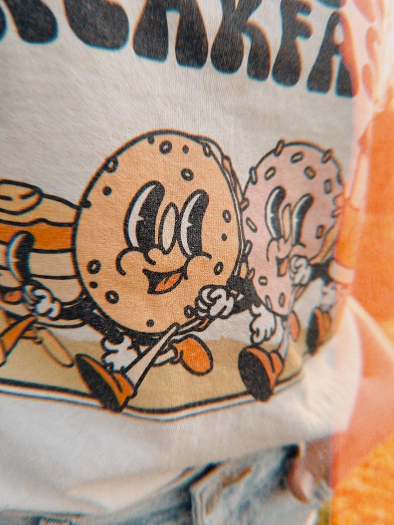 zoomed in detail of a retro graphic of a bagel and donut and pancakes walking
