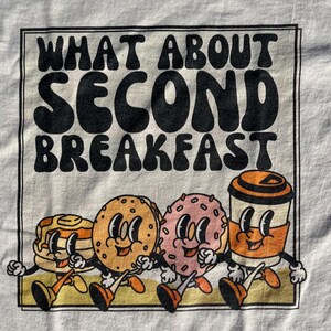 detail of the retro graphic of breakfast and title “what about second breakfast” perfect shirt for lord of the rings fans