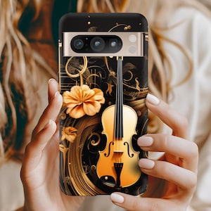 May include: A black phone case with a gold violin and flower design. The phone case has a camera lens cutout and a gold trim.