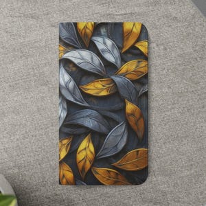 May include: A rectangular case featuring a repeating pattern of stylized leaves. The leaves are in shades of silver and gold, set against a dark gray background. The case has a smooth, glossy finish.