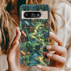 May include: A phone case featuring a detailed illustration of a quaint village nestled in a lush forest. The artwork depicts charming houses with orange and blue roofs, a winding river, and a pathway. The case has a dark green top and a gold-colored camera bar.