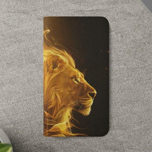 May include: Black wallet case featuring a golden lion's profile with a fiery mane against a dark background. The lion's face is detailed, with a focus on its eye and nose. The case is rectangular and appears to be made of leather.