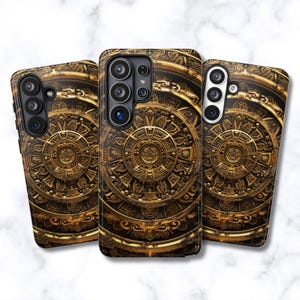 May include: Three phone cases with a detailed, golden Aztec calendar design on a dark brown background. The cases have camera cutouts and a glossy finish, showcasing intricate patterns and textures. The cases are for different phone models.