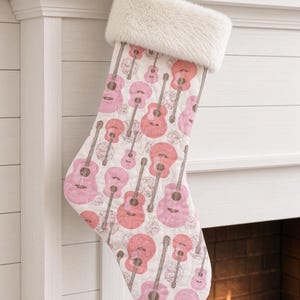 Peut inclure: Une chaussette de Noël matelassée ornée d'un motif répétitif de guitares acoustiques roses et corail sur fond blanc. La chaussette présente un revers en fausse fourrure blanche douce sur le dessus et une petite boucle en tissu pour l'accrocher.