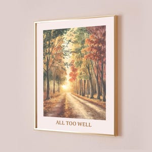 以下が含まれることがあります： 秋の森の中を走る道を描いた水彩画の額装プリント。木々は緑、黄色、オレンジ、赤と色とりどり。土の道は遠くの明るい光に向かって伸びている。画像の下には「ALL TOO WELL」という文字が印刷されている。