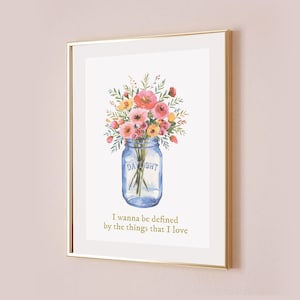 May include: A watercolor painting of a bouquet of pink, yellow, and red flowers in a blue mason jar with the word "DAYLIGHT" printed on the side. The text "I wanna be defined by the things that I love" is printed below the jar.