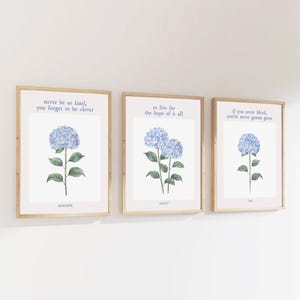 May include: Three framed prints featuring watercolour illustrations of blue hydrangeas and inspirational quotes. The first print reads "never be so kind, you forget to be clever" and is titled "MARIORE". The second print reads "to live for the hope of it all" and is titled "AUGUST". The third print reads "if you never bleed, you're never gonna grow" and is titled "TML".