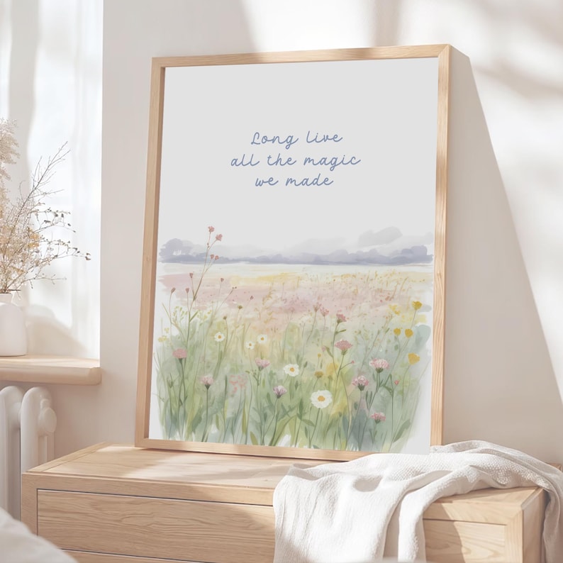 May include: A framed watercolor print featuring a field of wildflowers in soft pastel colors. The artwork includes the text "Long live all the magic we made" in a delicate script. The frame is made of light-colored wood.