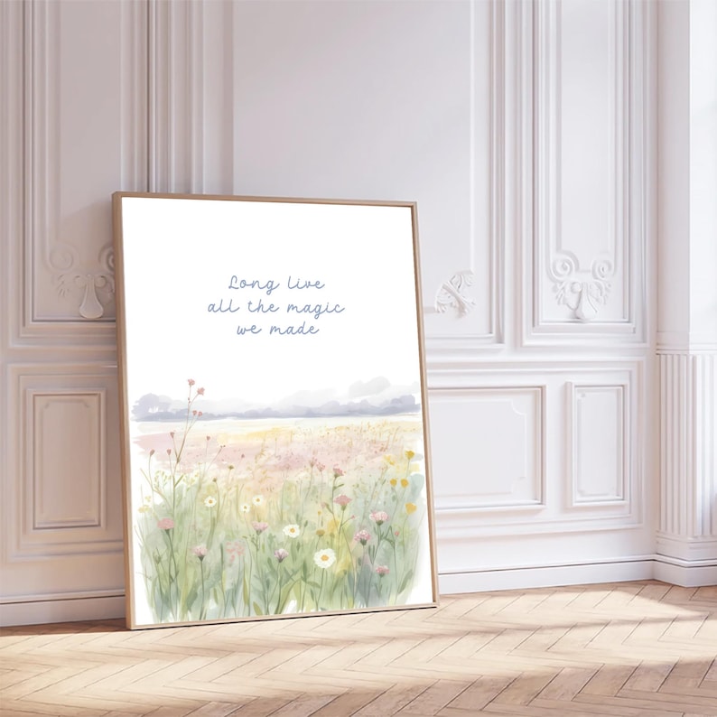 May include: A framed watercolor print featuring a field of wildflowers in soft pinks, yellows, and greens. The artwork includes the text "Long Live all the magic we made" in light blue script. The frame is a light brown color.