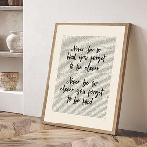 May include: A framed art print with a light beige background and a wooden frame. The print features the text "Never be so kind, you forget to be clever" and "Never be so clever, you forget to be kind" in a handwritten style.