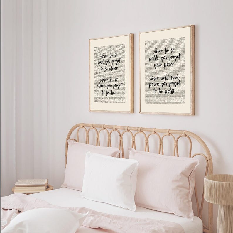 May include: Two framed prints with inspirational quotes in black script. The prints are in light wood frames and hang above a bed with pink bedding. The quotes include phrases like "Never be so kind you forget to be clever."