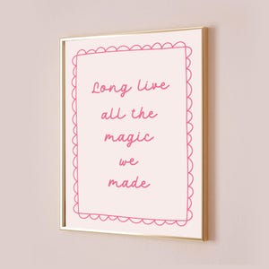 May include: A pink framed print with a white background and pink text that reads "Long live all the magic we made". The text is surrounded by a pink scalloped border.