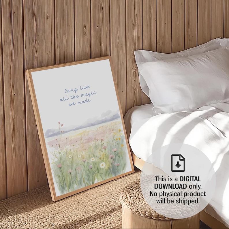 May include: A framed art print with the text "Long live all the magic we made" in blue script. The artwork depicts a watercolor landscape of a field with wildflowers. The frame is light brown.