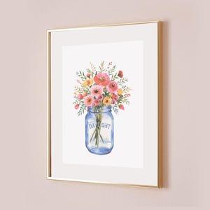 May include: Watercolor painting of a bouquet of pink, orange, and yellow flowers in a blue mason jar. The jar has the word "DAYLIGHT" printed on it. The artwork is framed in a gold frame.