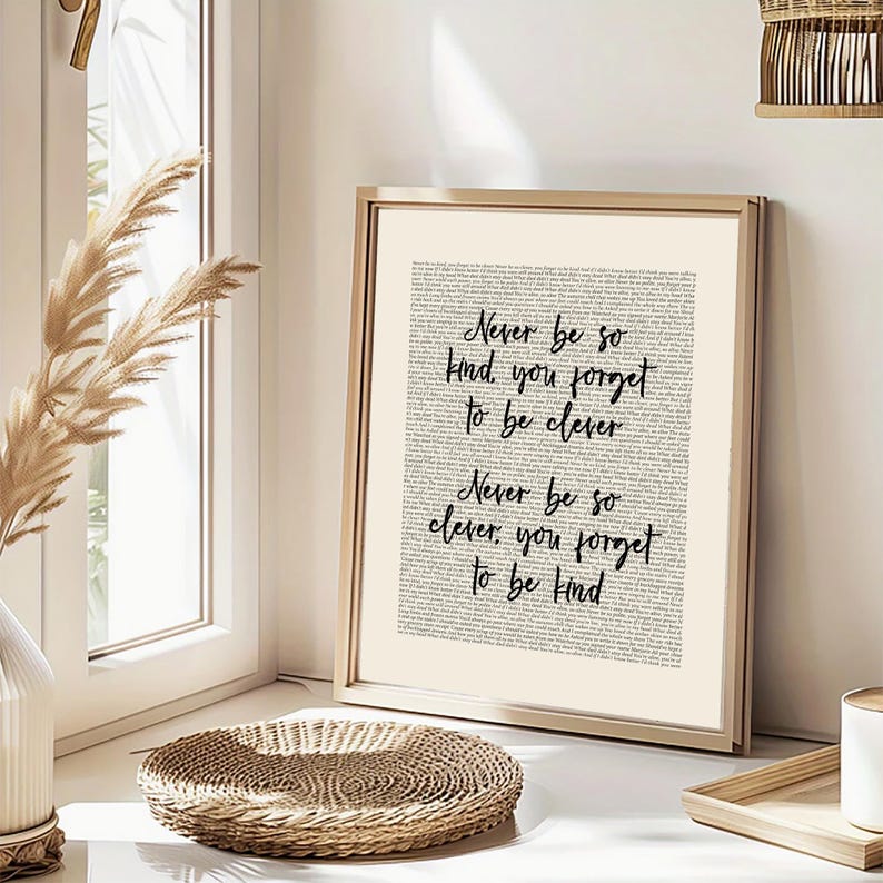 May include: A framed print with the text "Never be so kind, you forget to be clever. Never be so clever, you forget to be kind" in black script. The background is a light beige colour, and the frame is gold.