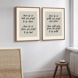 May include: Two framed art prints with inspirational quotes in black script on a cream background. The frames are a warm brown. The quotes include phrases like "Never be so kind, you forget to be clever."