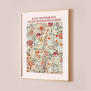 以下が含まれることがあります： 赤、オレンジ、青の色合いの花柄が描かれた額装されたプリント。プリントの上部には「If you never bleed, you're never gonna grow」というテキストが赤色で印刷されています。
