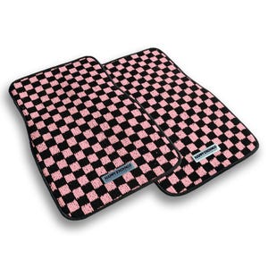 May include: Two rectangular car floor mats featuring a repeating black and pink checkered pattern. Each mat has a black border and a small rectangular label near the bottom edge with the text HAPPY ENDINGS printed in black on a light background.