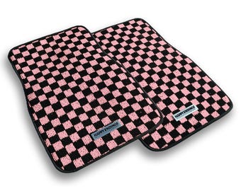 May include: Two rectangular car floor mats featuring a repeating black and pink checkered pattern. Each mat has a black border and a small rectangular label near the bottom edge with the text HAPPY ENDINGS printed in black on a light background.