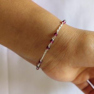 May include: A silver chain bracelet with small purple beads.