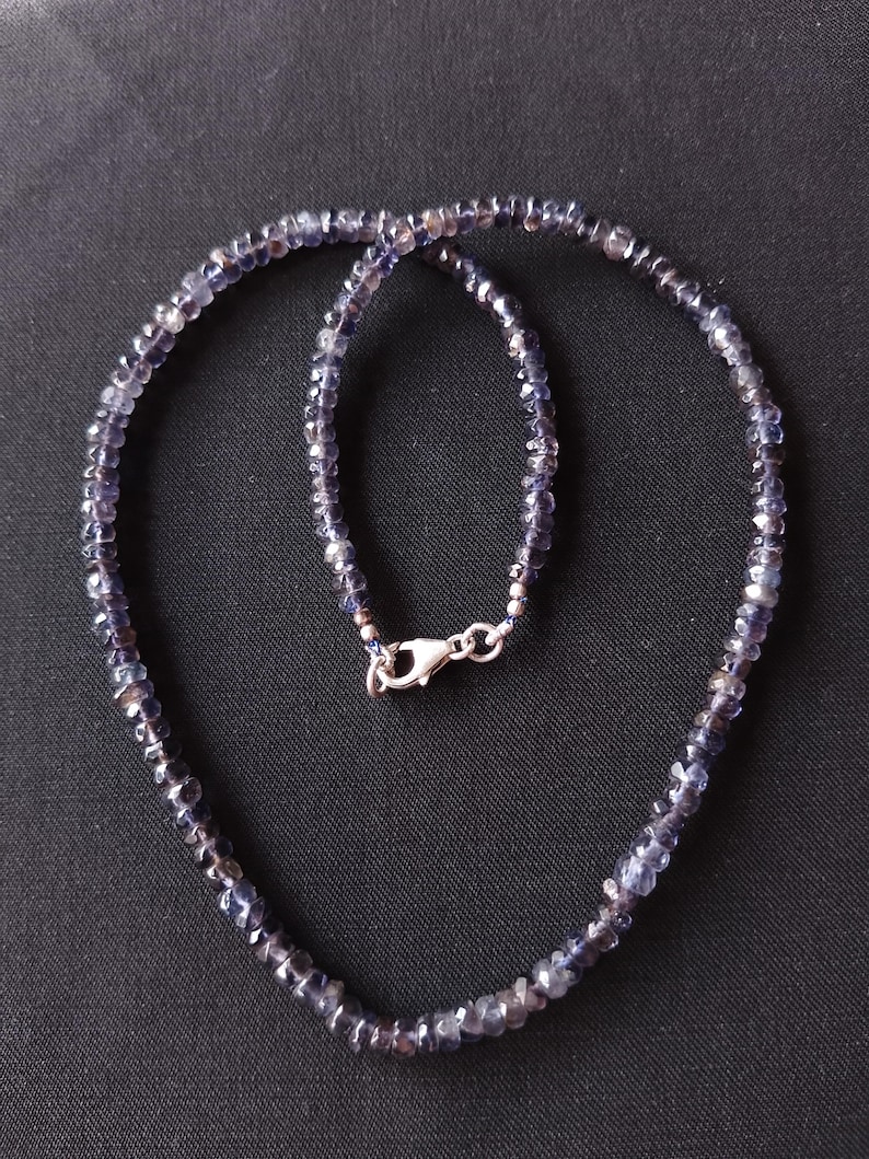 May include: A silver chain necklace with a silver clasp, featuring a strand of dark blue gemstone beads.