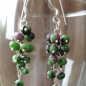 May include: A pair of silver dangle earrings with green and pink gemstone beads. The beads are arranged in a cascading cluster.