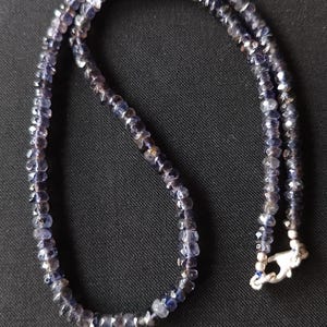 May include: A necklace made of dark blue faceted gemstone beads with a silver clasp.