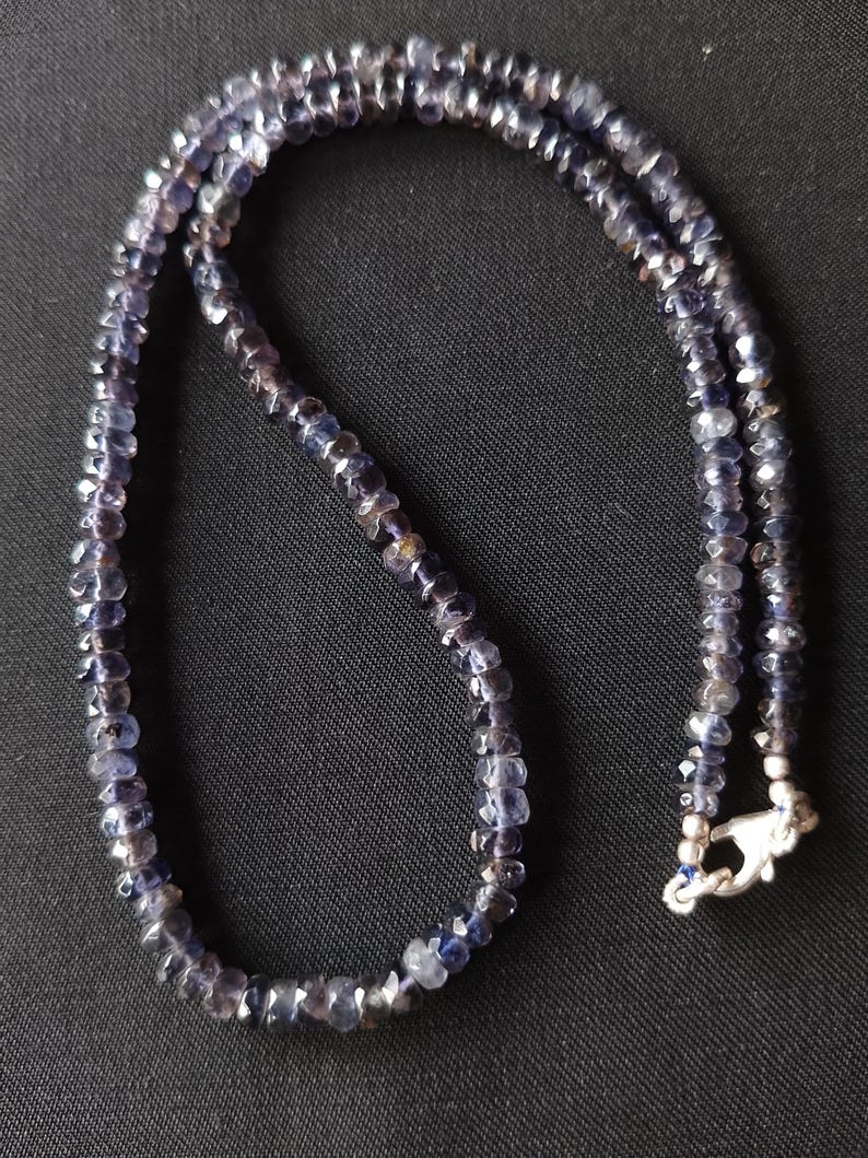 May include: A necklace made of dark blue faceted gemstone beads with a silver clasp.