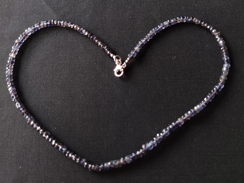 May include: A silver necklace with a heart-shaped chain made of small, dark blue gemstones.