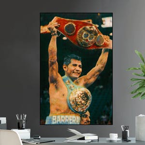 May include: A framed print of a boxer holding up two championship belts. The boxer is smiling, and the belts are red and gold. The word "BARRERA" is visible on the boxer's trunks. The image is a portrait.