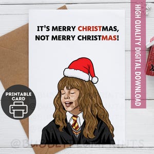 May include: A white printable Christmas card with the text "IT'S MERRY CHRISTMAS, NOT MERRY CHRISTMAS!". The card features a cartoon of a person wearing a Santa hat. A brown envelope is behind the card.