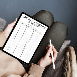 May include: A digital tablet displaying a spreadsheet with the title "10K in 6 Months *Bi-Weekly*" and a column for "Deposit" and "Balance". The spreadsheet shows a plan to save $10,000 in six months by making bi-weekly deposits.