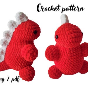 May include: Two red crocheted dinosaur plush toys with white dorsal spikes and black bead eyes. The text "Crochet pattern" appears at the top right, and the text "eng / pdf" appears at the bottom left of the image.