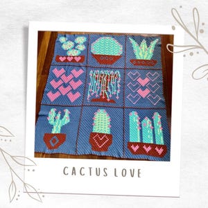 May include: A crocheted blanket with a blue background and various cactus designs in shades of green, pink, and brown. The blanket is divided into nine squares, each featuring a different cactus design. The blanket is labelled "Cactus Love".