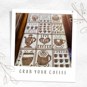 May include: A crocheted coffee-themed blanket with squares featuring different coffee-related designs, including coffee cups, coffee beans, and the words "Grab Your Coffee", "Iced Coffee", "Live Love Coffee", "Latte", and "Espresso".