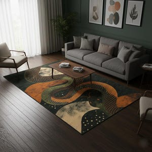 Op de afbeelding: Een rechthoekig vloerkleed met een slangenontwerp in groen, oranje en beige tinten. Het kleed ligt in een woonkamer met een grijze bank, een houten salontafel en kunst aan de muur. Het ontwerp van het kleed toont een gestileerde slang.