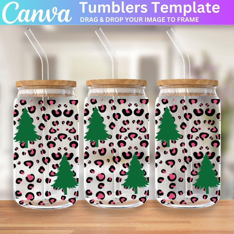 May include: Three clear glass tumblers with wooden lids and pink and black leopard print designs with green Christmas trees. Each tumbler has a clear plastic straw.