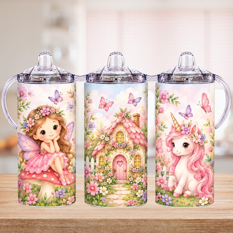 Op de afbeelding: Drie doorzichtige plastic tuitbekers met handvatten, elk voorzien van een kleurrijke illustratie. De ontwerpen tonen een fee op een paddenstoel, een klein huisje met een roze dak en een witte eenhoorn met roze manen en bloemen.