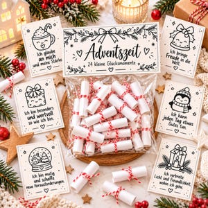 May include: A clear plastic bag filled with 24 small white paper scrolls tied with red and white twine, labeled Adventszeit 24 kleine Glücksmomente, surrounded by six illustrated cards featuring holiday icons and German text.