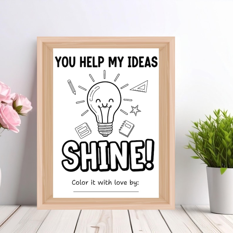 May include: A framed black and white print with the text "YOU HELP MY IDEAS SHINE!" and a lightbulb illustration. The print includes a space to be colored in and is surrounded by a light brown wooden frame. The image also includes a pencil, a protractor, a star, a notepad, and a calculator.