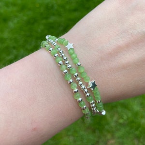 May include: Three layered bracelets with green gemstone beads and silver star charms.