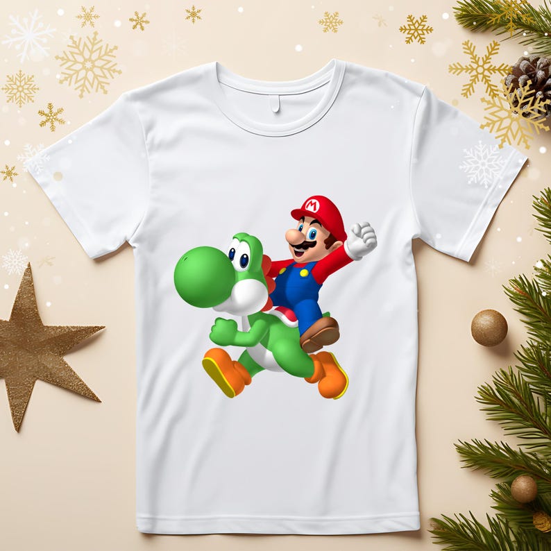 May include: White t-shirt featuring a colorful graphic of Mario riding Yoshi. Mario is wearing a red hat, blue overalls, and a red shirt. Yoshi is green with orange shoes. The design is centered on the shirt.