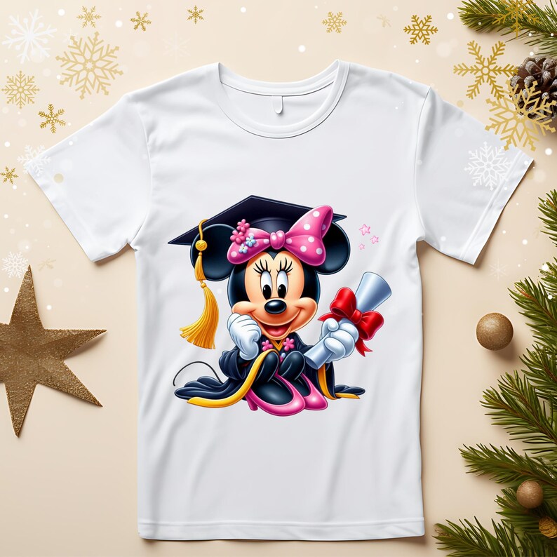 May include: White t-shirt featuring a cartoon Minnie Mouse in a graduation cap and gown, holding a diploma tied with a red bow. Minnie Mouse has a pink polka-dot bow and is surrounded by stars. The design is festive and celebratory.