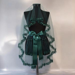 May include: A green tulle wedding veil with a beaded trim and a matching green satin ribbon.