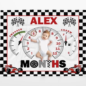 May include: A white baby blanket with a black and white checkered border. The center of the blanket features a speedometer with the name "ALEX" and the word "MONTHS" printed below. Two red race cars are on either side of the speedometer.