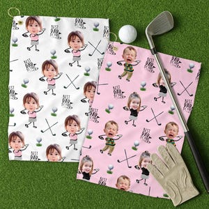 May include: Two golf towels with a repeating pattern of cartoon children, golf clubs, and golf balls. One towel is white, the other is pink. Text on the towels reads "BEST DAD BY PAR". A golf club, ball, and glove are also present.