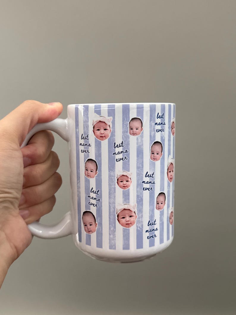 May include: White ceramic mug with a blue and white striped pattern. The mug is decorated with baby photos and the text "best mama ever". The mug has a white handle.