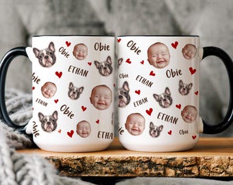 May include: Two white ceramic mugs with black handles and rims. The mugs are decorated with images of a baby's face, a French bulldog, red hearts, and the names "Obie" and "Ethan". The mugs are on a wooden surface.
