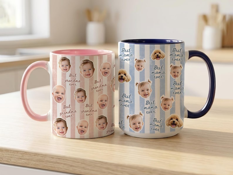 May include: Two ceramic mugs with personalized designs. One mug features a pink handle and interior with a pattern of baby faces and the text "Best grandma ever." The other mug has a blue handle and interior, with baby faces, puppies, and the text "Best mama ever."